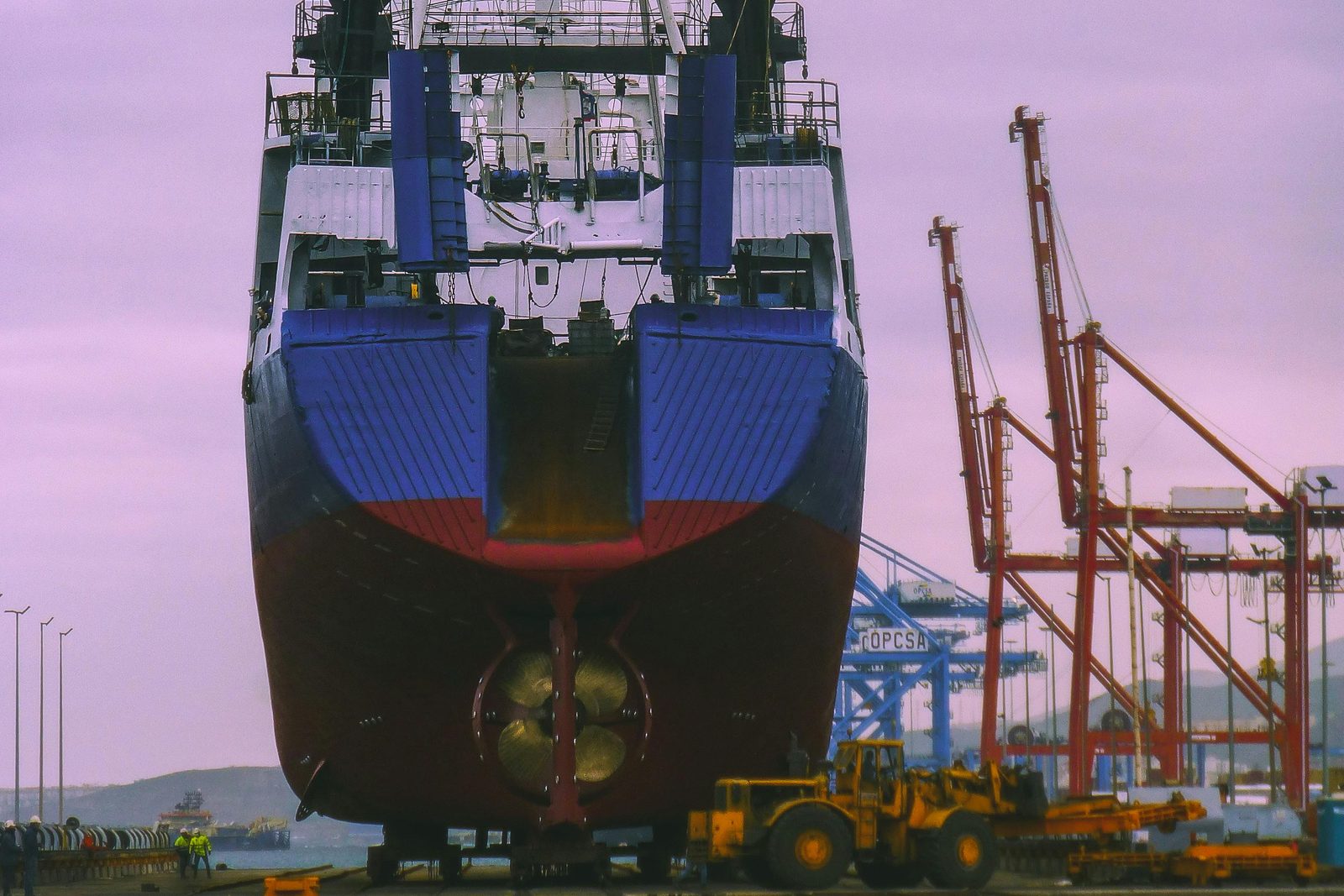 A vessel on shipyard launch rails, flanked by gantry cranes, during a new build delivery